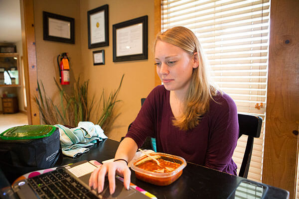 woman eating while browsing on laptop